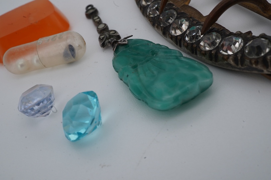 A collection of jewels and a loose sapphire, comprising: a shoe buckle set with colourless pastes, length 6.8cm; a green paste and marcasite pendant imitating jadeite; a polished slab of carnelian; a loose cushion-shaped